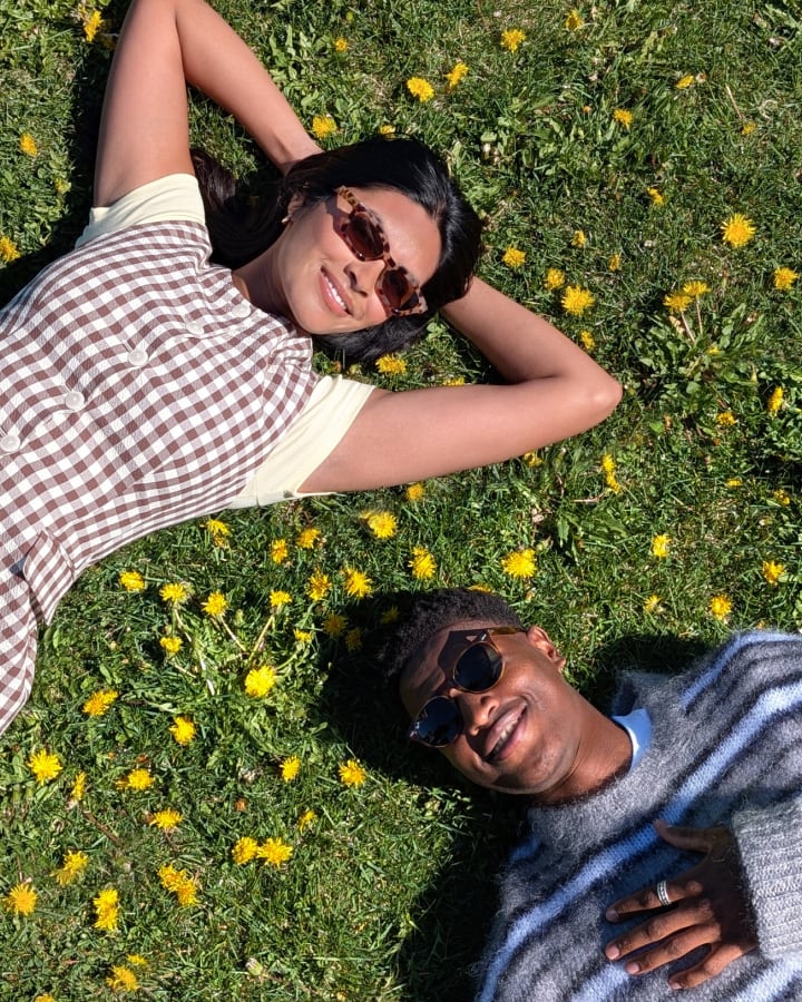 Top-down photo of two people with sunglasses in lying in a field of sunny flowers