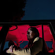 A person sits in a car during the night. The interior glows red.